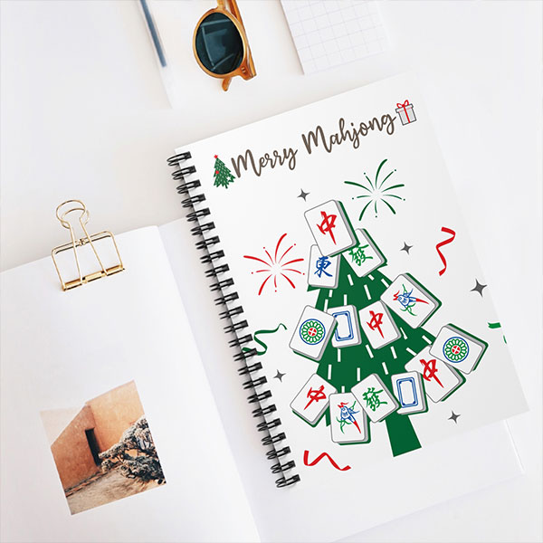 Mahjong-themed spiral notebook featuring mahjong tile tree illustration on cover, styled on desk with stationery