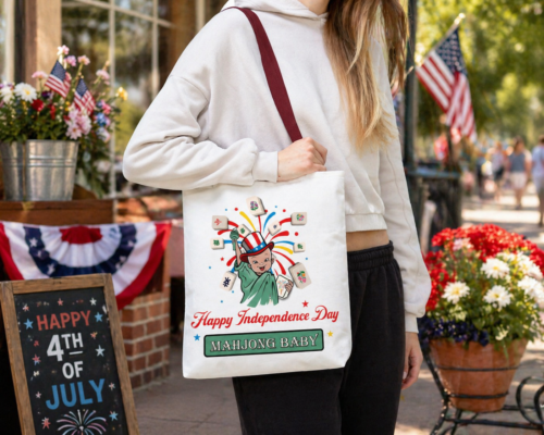 Mahjong Baby 4th of July tote bag worn by woman outdoors, patriotic mahjong tote with Lady Liberty design, Independence Day market bag